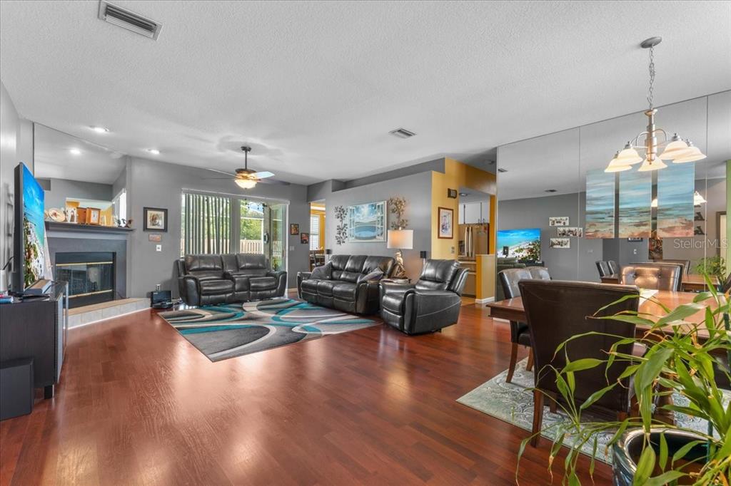 A spacious living and dining area features dark wood floors, leather furniture, and mirrored walls — 22804 WILLOW LAKES DRIVE, LUTZ, FL