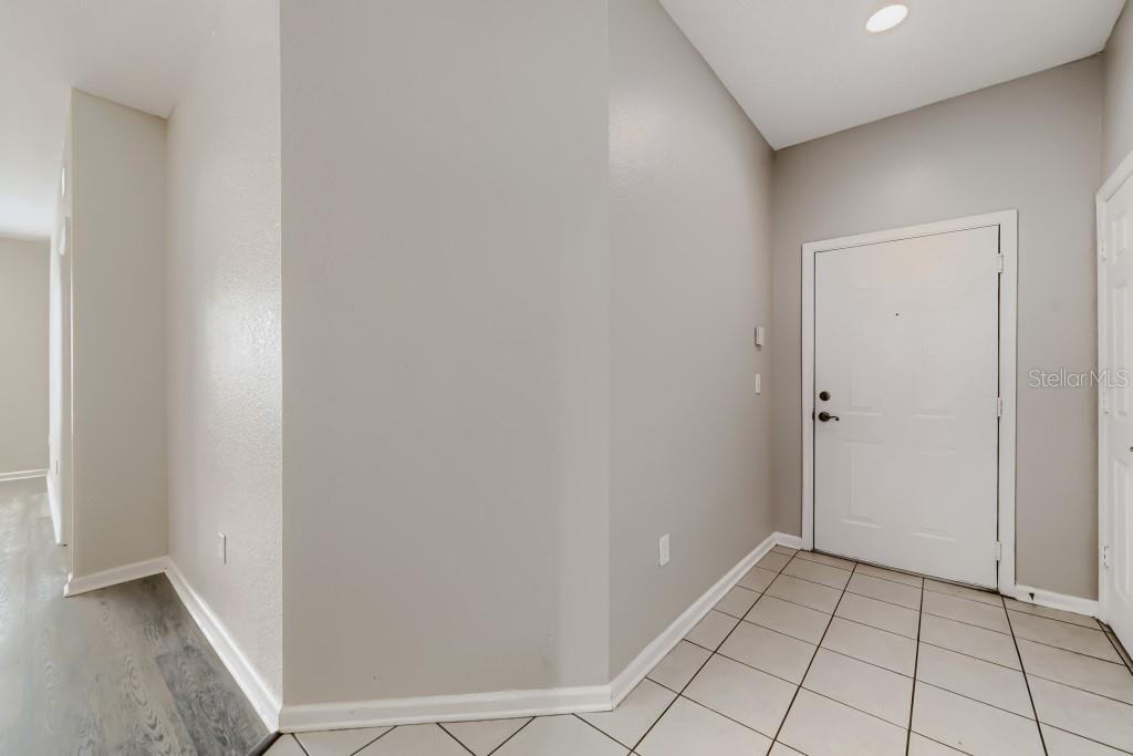An entryway features light gray walls, tiled flooring, and a white front door — 6380 CONTESSA DRIVE UNIT 304, ORLANDO, FL