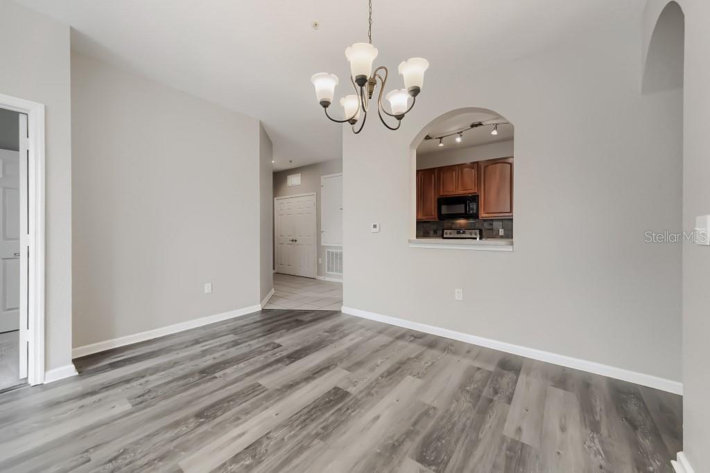 A dining area with wood-look flooring, a chandelier, and an arched pass-through to the kitchen — 6380 CONTESSA DRIVE UNIT 304, ORLANDO, FL