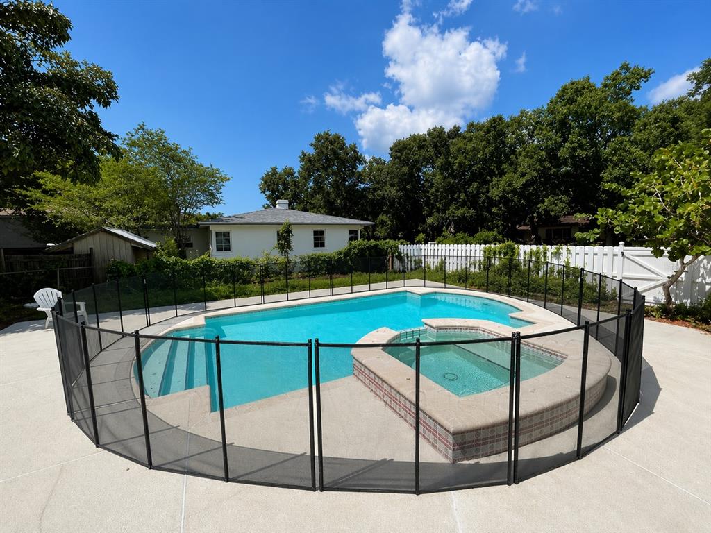 A backyard swimming pool and attached hot tub are enclosed by a black mesh safety fence — 1225 11TH STREET N, ST PETERSBURG, FL