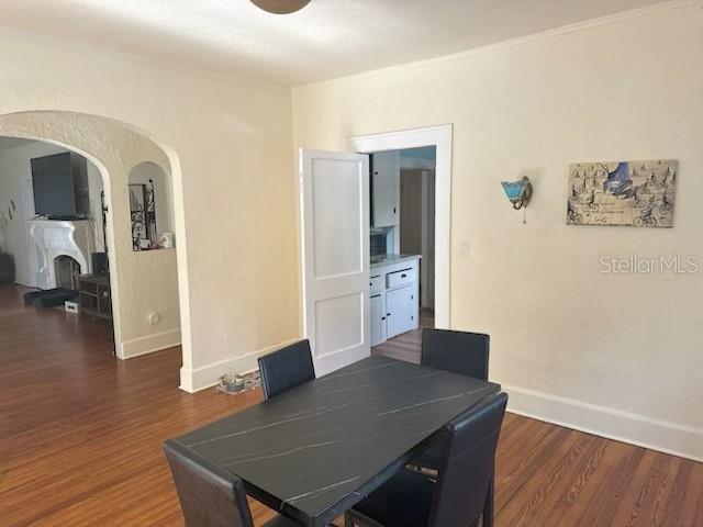 A dining area with a dark table, hardwood floors, and an arched doorway to another room — 1225 11TH STREET N, ST PETERSBURG, FL