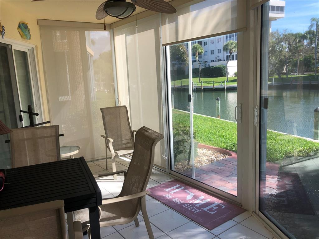 A sunroom with tile floors, patio furniture, and sliding glass doors overlooking a canal — 1250 N PORTOFINO DRIVE UNIT 102MAR, SARASOTA, FL