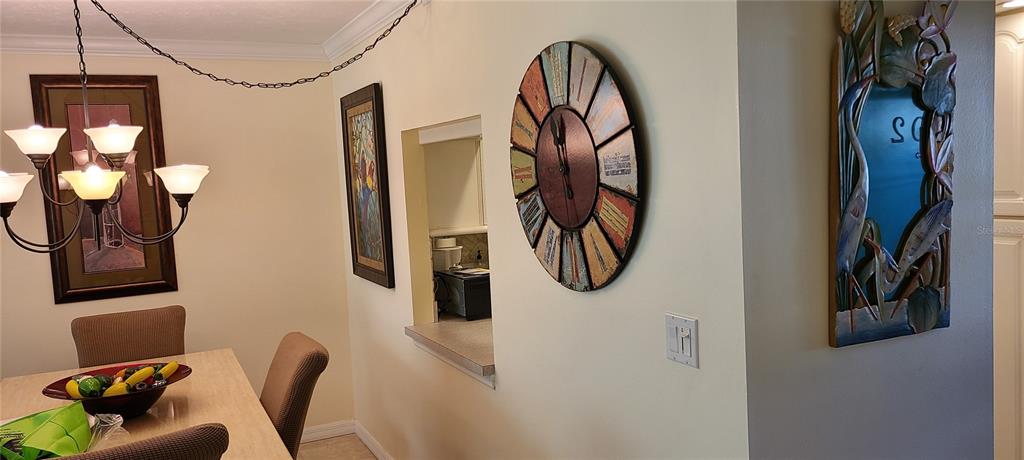 A dining area features a chandelier, a wall clock, and a decorative mirror on the wall — 1250 N PORTOFINO DRIVE UNIT 102MAR, SARASOTA, FL