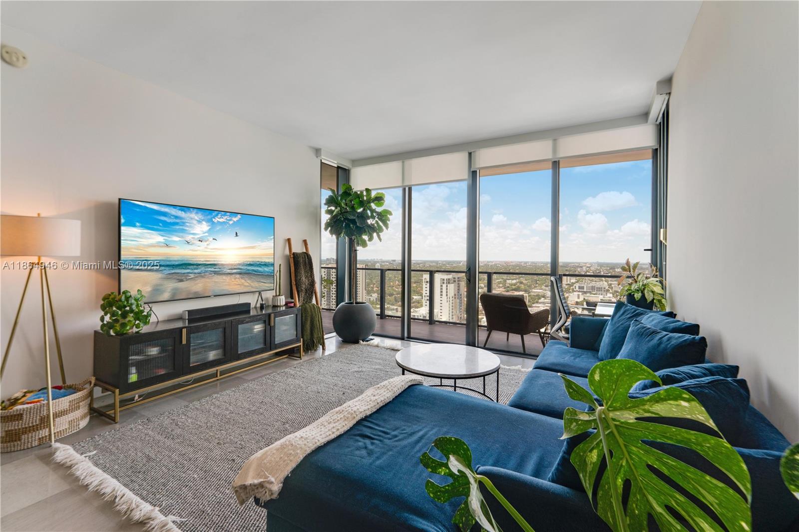 A modern living room features a blue sectional sofa, media console, and floor-to-ceiling windows — 88 SW 7th St # 2910, Miami FL 33130, MIAMI, FL