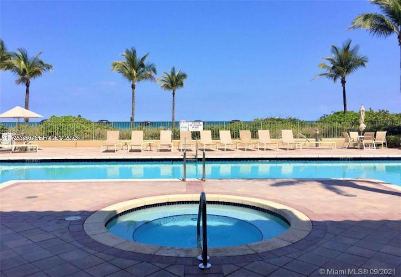 A round hot tub sits in the foreground of a pool deck with lounge chairs — 2080 S Ocean Dr # 502, Hallandale Beach FL 33009, HALLANDALE BEACH, FL