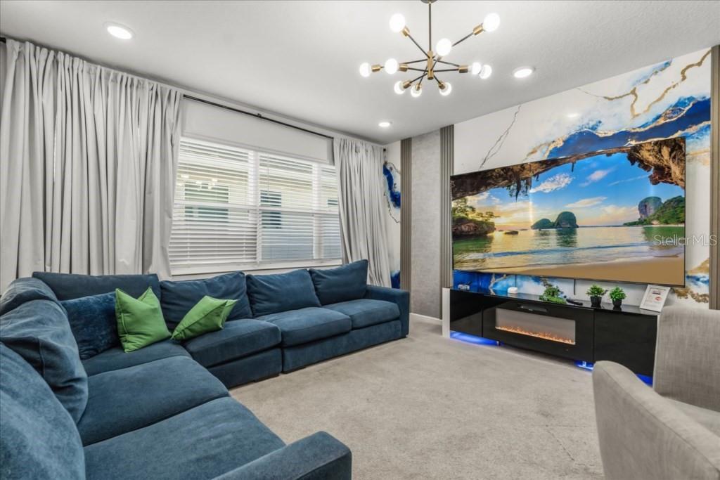 A living room features a large blue sectional sofa, a fireplace console, and a marble-patterned wall — 2558 SHANTI DRIVE, KISSIMMEE, FL