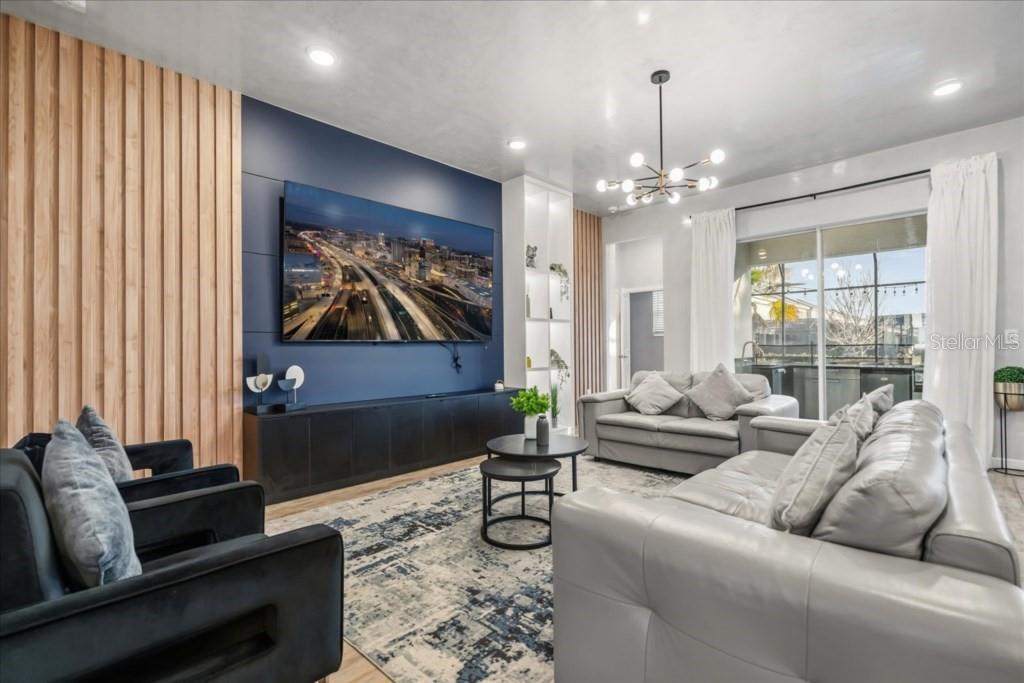 A living room features a dark blue accent wall, wood slat paneling, and gray furniture — 2558 SHANTI DRIVE, KISSIMMEE, FL