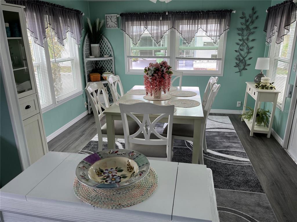 A dining room features a white table and chairs, teal walls, and gray flooring — 1413 24TH AVENUE W, BRADENTON, FL