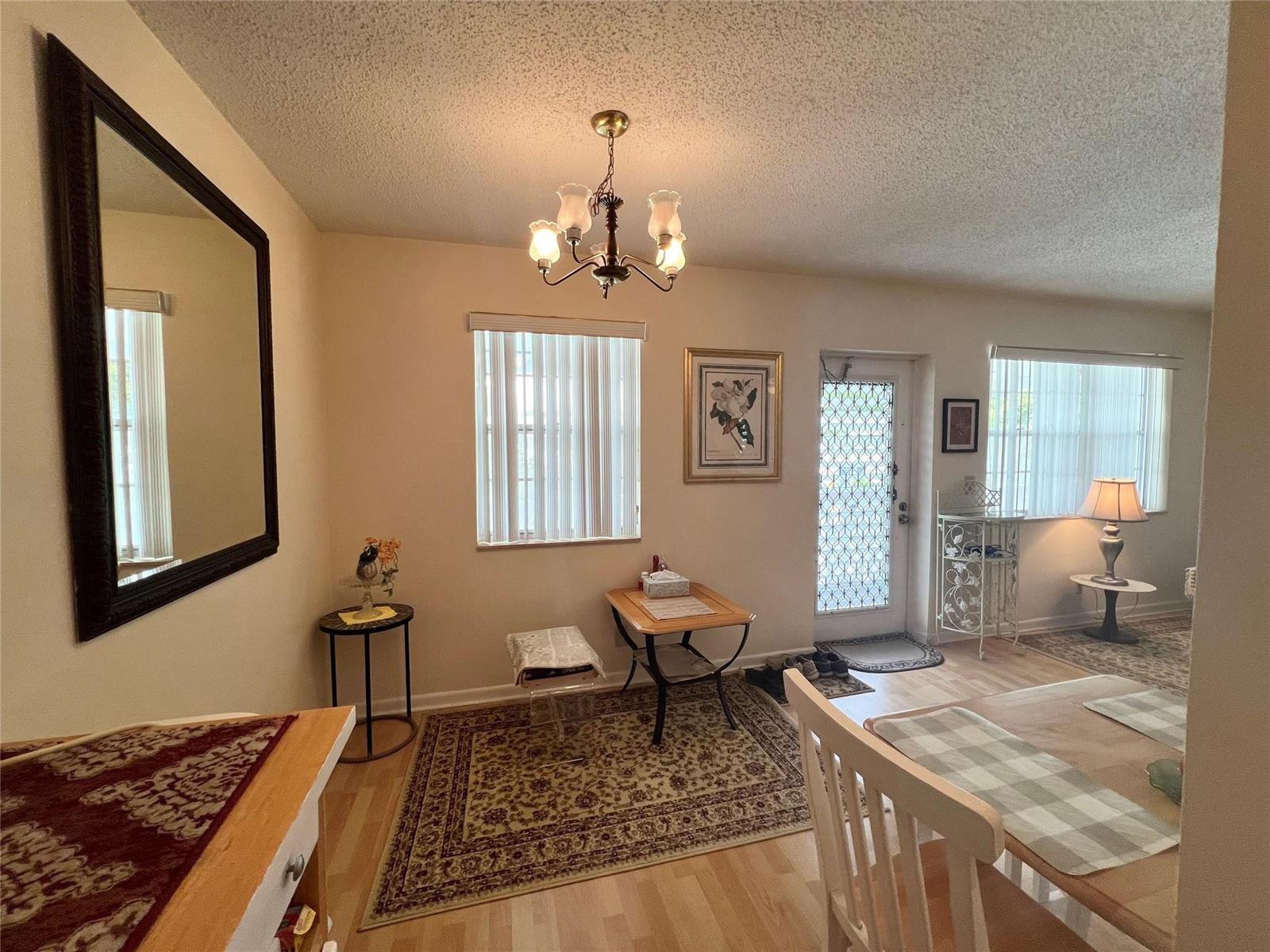 A dining area features a chandelier, a large mirror, light wood flooring, and two windows — 191 Markham I # 191, Deerfield Beach FL 33442, DEERFIELD BEACH, FL