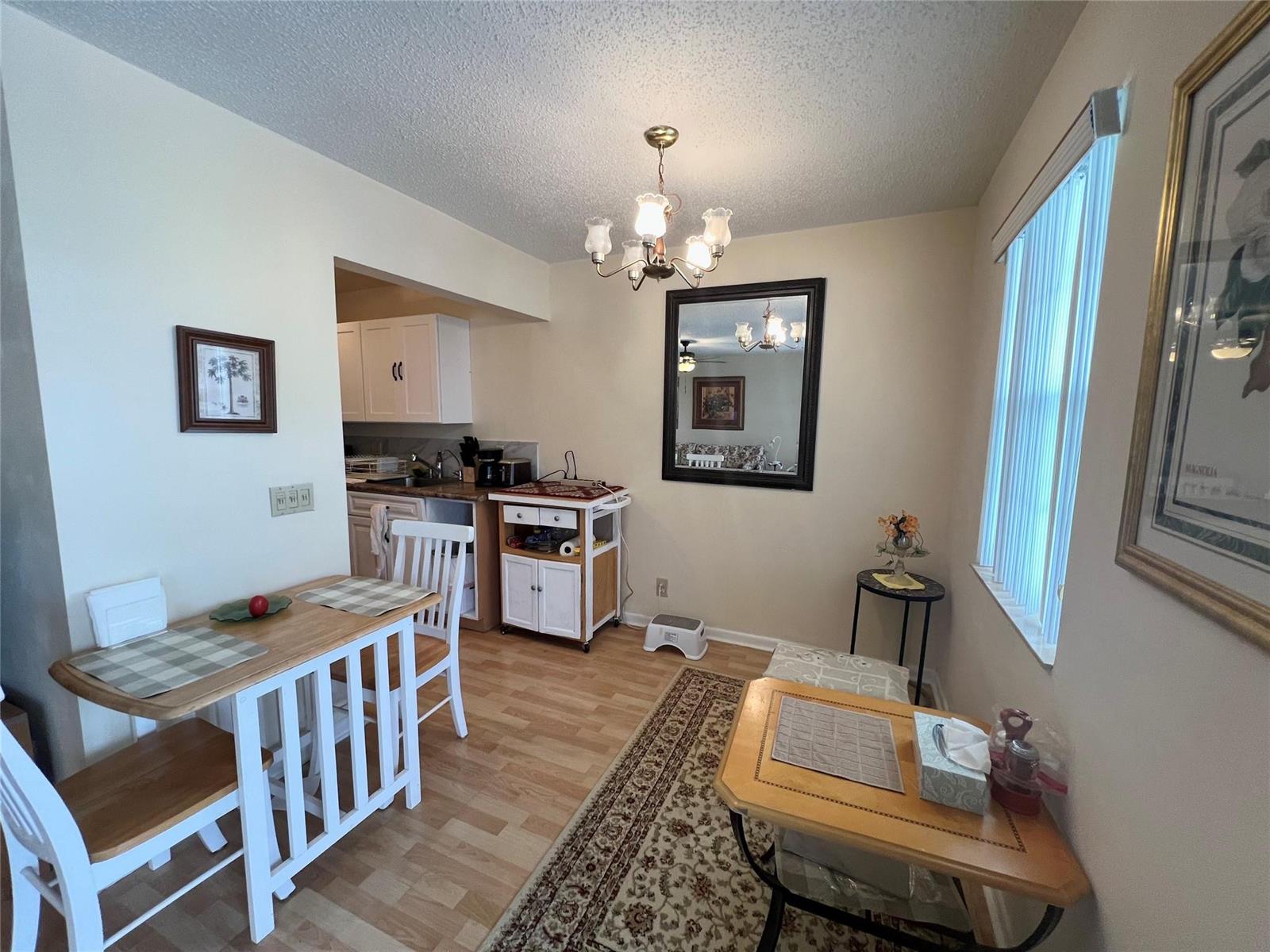 A dining area features a wooden table, a small side table, and a kitchen pass-through — 191 Markham I # 191, Deerfield Beach FL 33442, DEERFIELD BEACH, FL