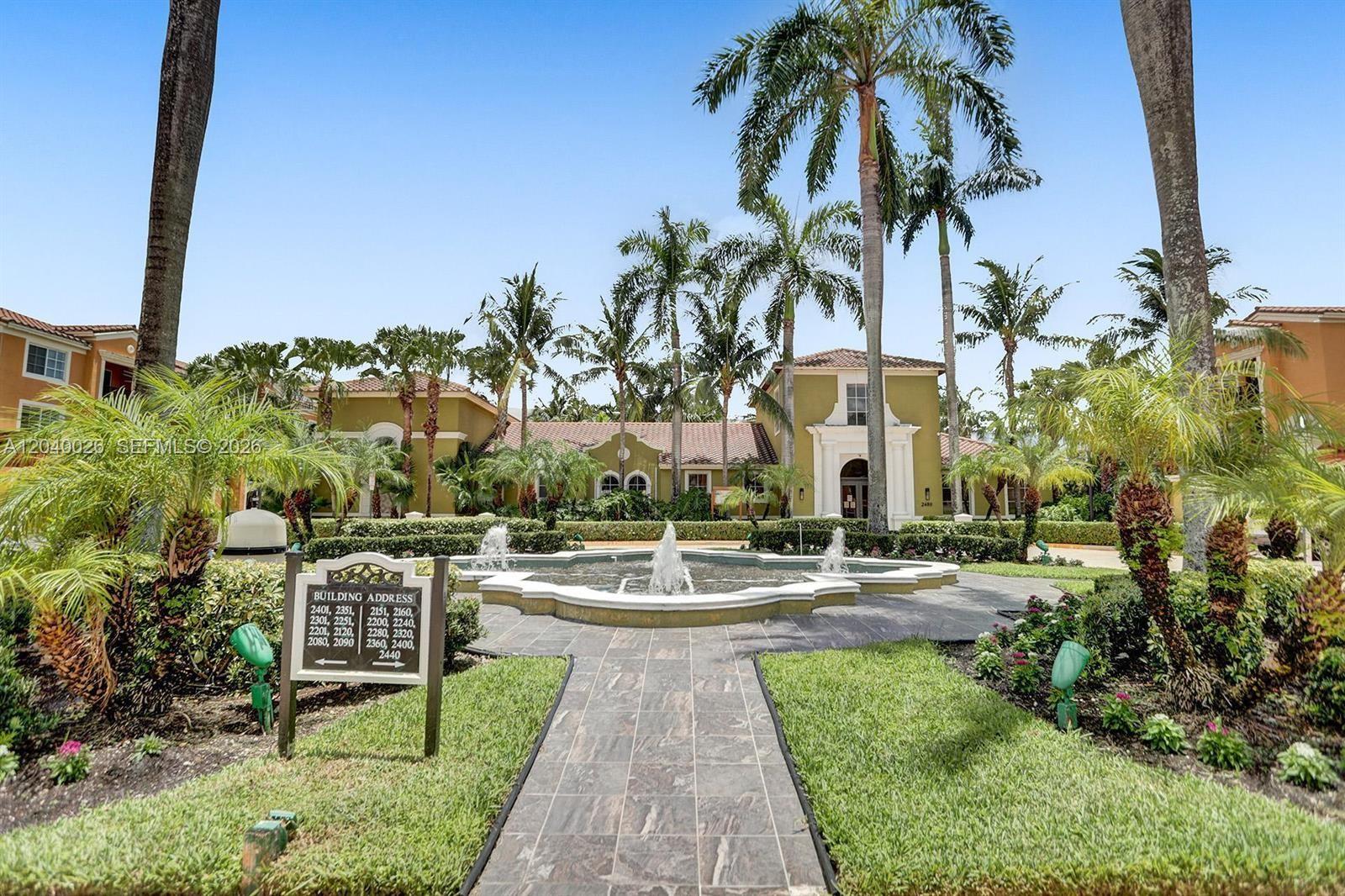 A paved walkway leads to a central fountain in front of a multi-story apartment complex — 2240 E Preserve Way # 104, Miramar FL 33025, MIRAMAR, FL