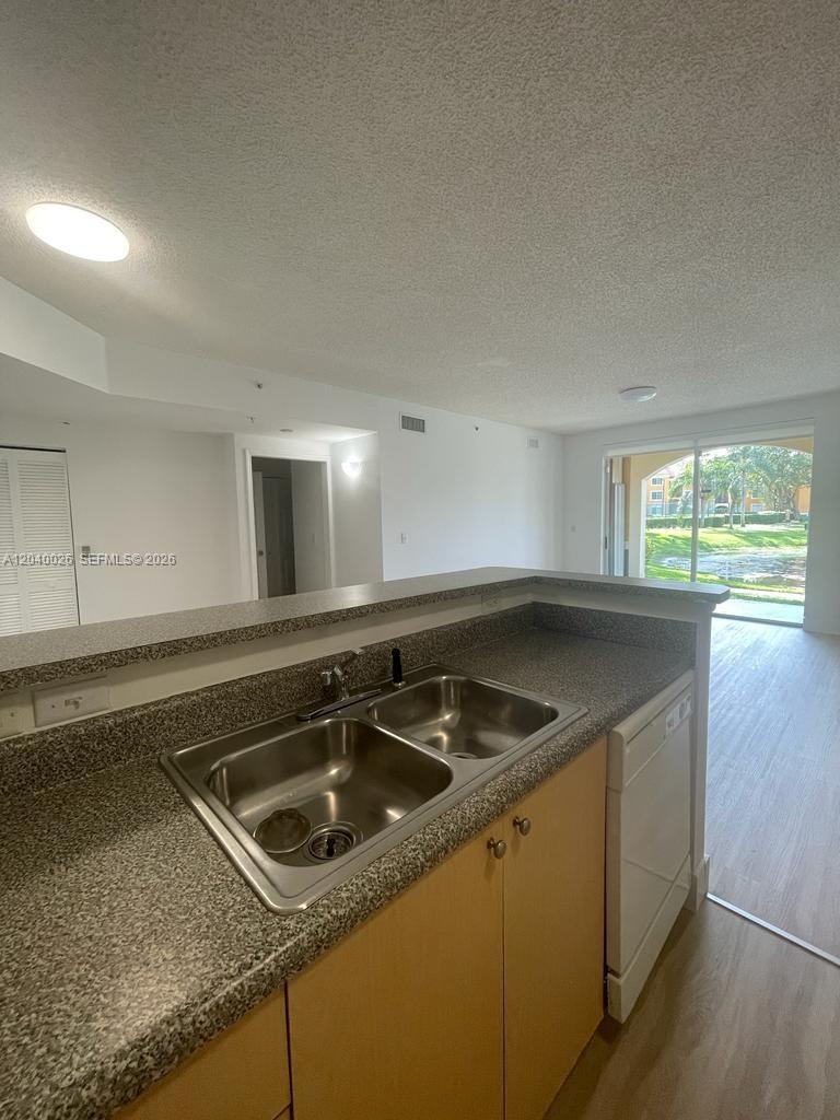 A kitchen sink with granite countertops overlooks a living area with a sliding glass door — 2240 E Preserve Way # 104, Miramar FL 33025, MIRAMAR, FL