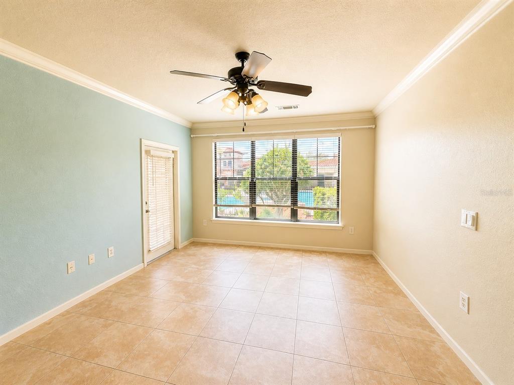 An empty room with light tile floors, a ceiling fan, and a view of a pool — 907 CHARO PARKWAY UNIT 915, DAVENPORT, FL
