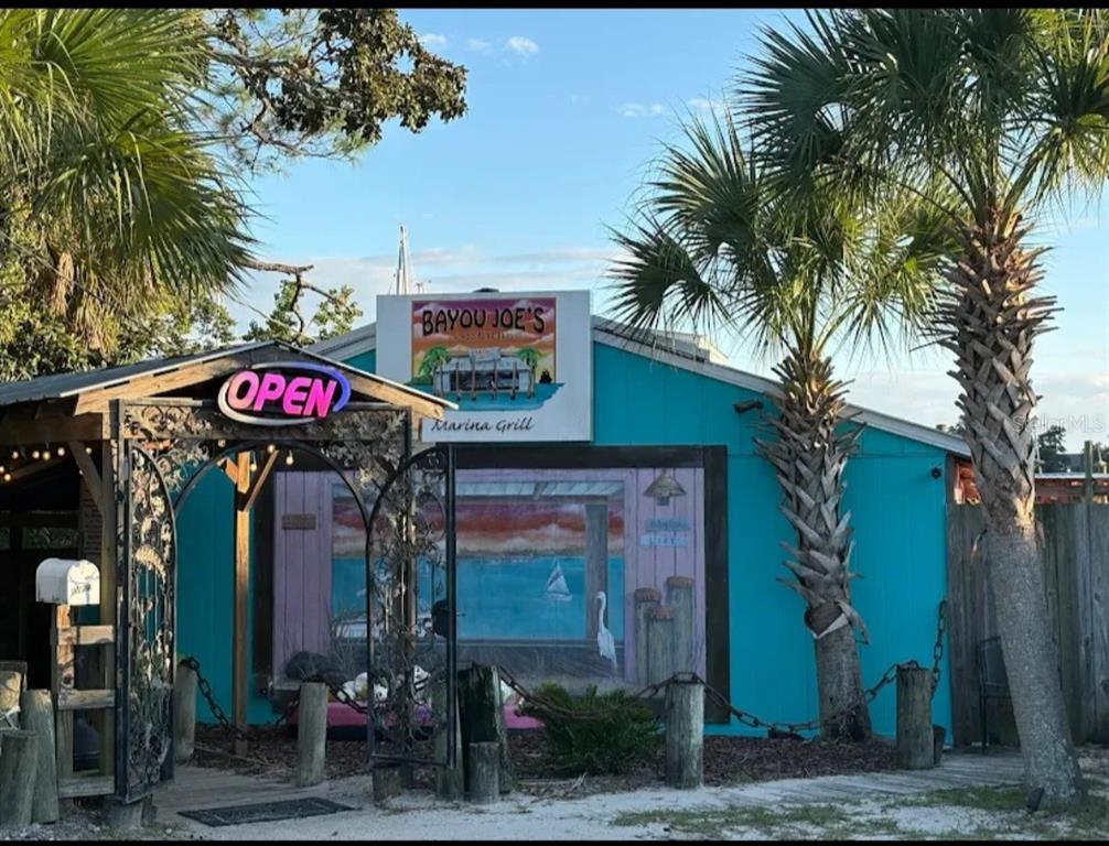 The exterior of Bayou Joe's Marina Grill features a teal building with a mural and palms — 7901 HIGHWAY 2301, PANAMA CITY, FL