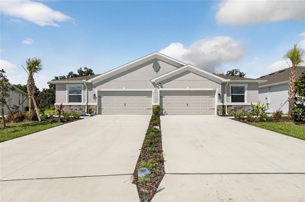 A duplex home with two garage doors, a concrete driveway, and a landscaped front yard — 4025 WESTWOOD FIELDS LOOP, PLANT CITY, FL