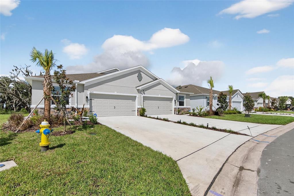 A street-level view of a light gray suburban house with a two-car garage and driveway — 4025 WESTWOOD FIELDS LOOP, PLANT CITY, FL