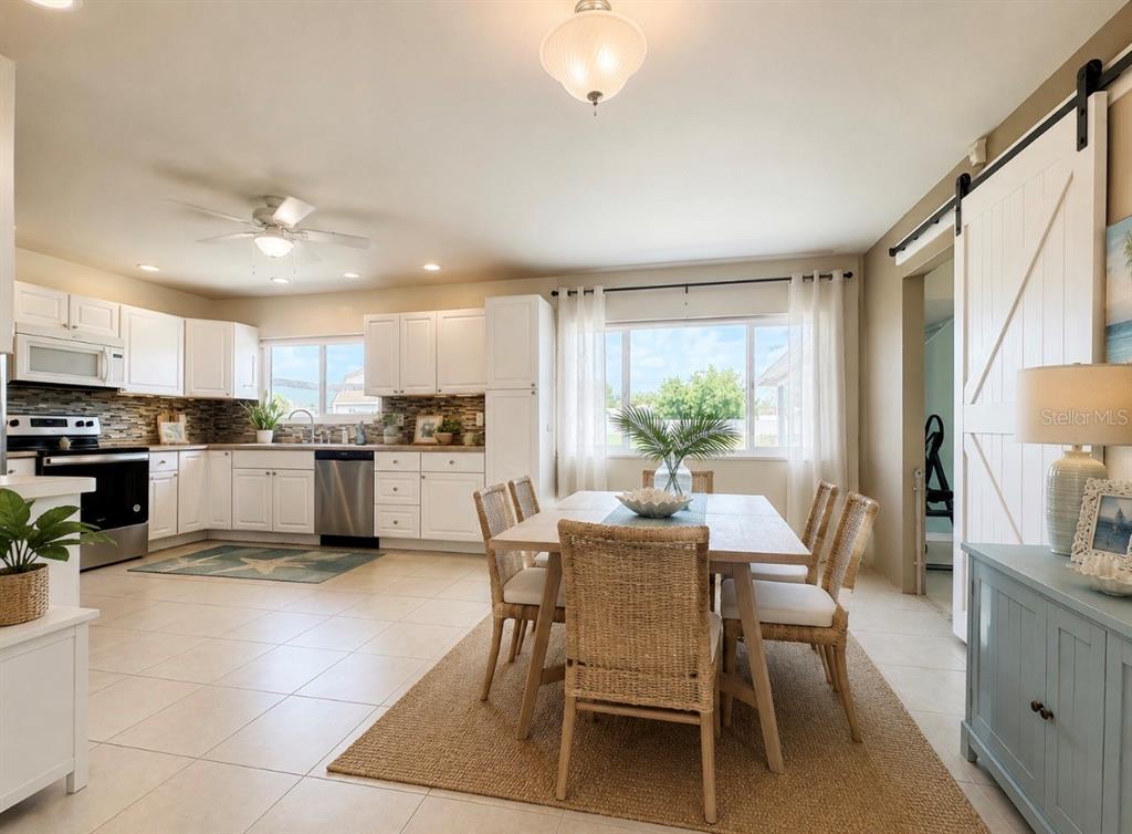 A kitchen and dining area with white cabinets, tile floors, and a sliding barn door — 2755 GREENDALE ROAD, NORTH PORT, FL