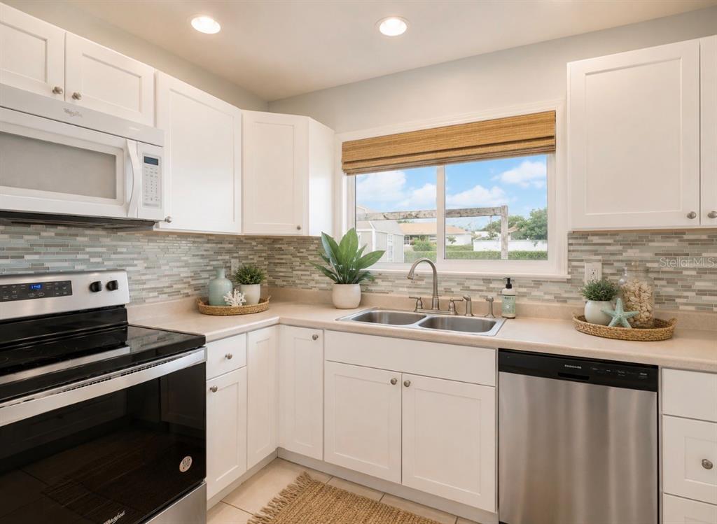A kitchen with white cabinets, stainless steel appliances, a tile backsplash, and a window — 2755 GREENDALE ROAD, NORTH PORT, FL