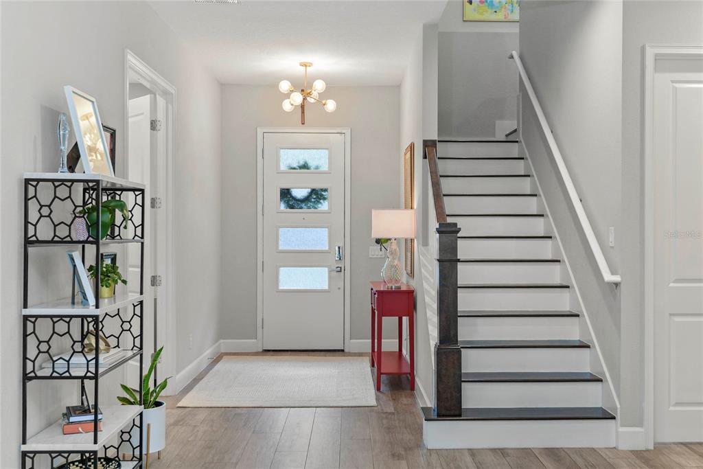 A bright entryway features a white front door, a staircase with dark treads, and shelving — 1438 W HARVARD STREET, ORLANDO, FL