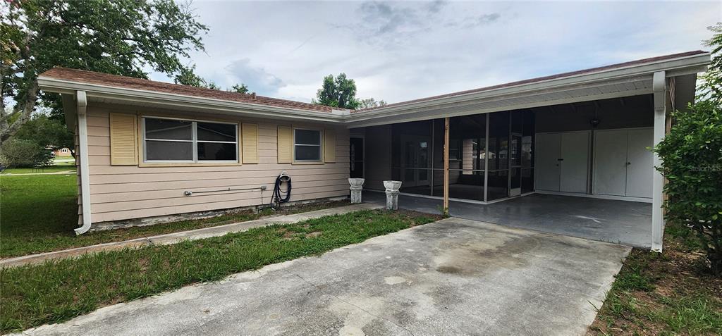 A single-story house exterior features tan siding, a concrete driveway, and a screened-in porch area — 3576 SW 147TH LANE ROAD, OCALA, FL