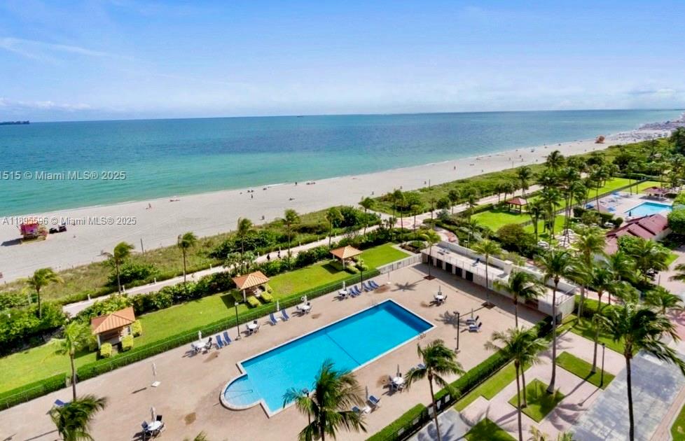 An aerial view shows a rectangular swimming pool, palm trees, and a sandy beach — 2625 Collins Ave # 1507, Miami Beach FL 33140, MIAMI BEACH, FL