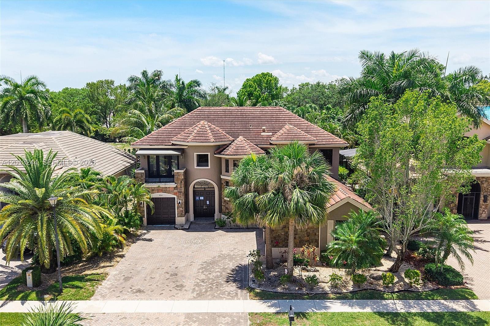A two-story house with a tiled roof, stone accents, and a paved driveway — 10364 Trianon Pl, Wellington FL 33449, WELLINGTON, FL