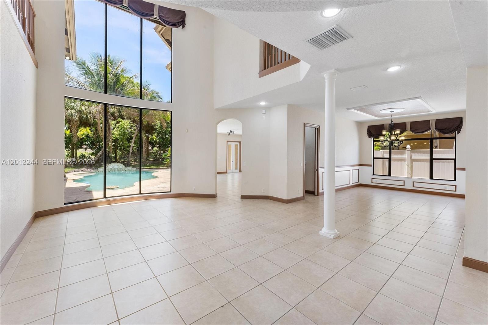 A spacious living room features tile floors, a tall window wall, and a central column — 10364 Trianon Pl, Wellington FL 33449, WELLINGTON, FL