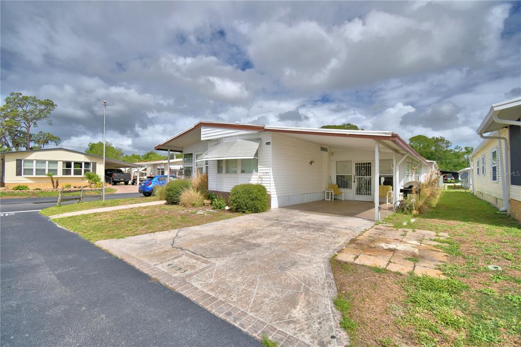 A single-story mobile home features white siding, a concrete driveway, and a covered carport — 4155 SPRUCEWOOD STREET, WINTER HAVEN, FL
