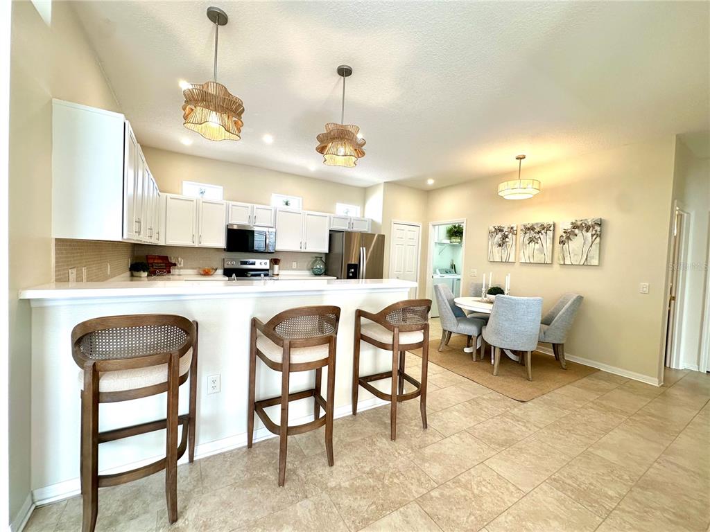 A kitchen with white cabinets and a breakfast bar opens to a dining area — 8137 PONKAN ROAD, LAND O LAKES, FL