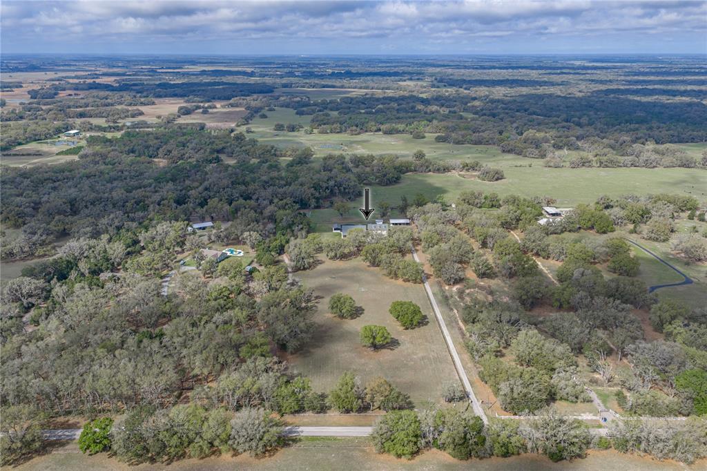 An aerial view shows a rural property with a house, outbuildings, and scattered trees — 15131 BELLAMY BROTHERS BOULEVARD, DADE CITY, FL