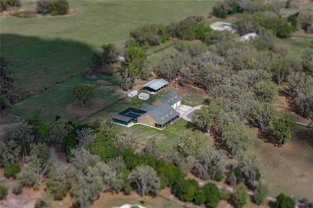 An aerial view shows a house with a pool and a detached garage on rural land — 15131 BELLAMY BROTHERS BOULEVARD, DADE CITY, FL