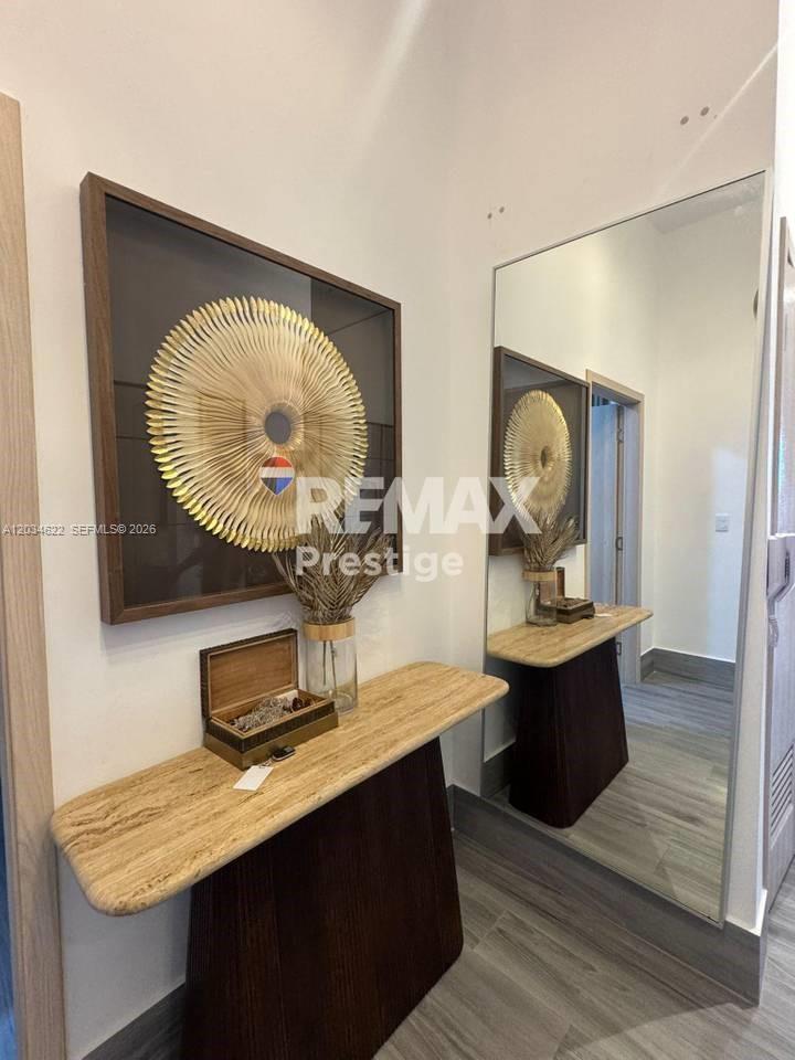 A console table with a decorative wall art piece sits in a mirrored entryway — 1 Vista alta # 1, FL