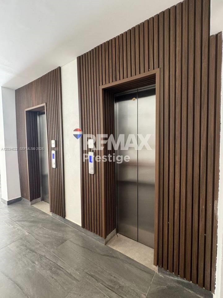 Two stainless steel elevators are set into a wall with vertical wood slat paneling — 1 Vista alta # 1, FL