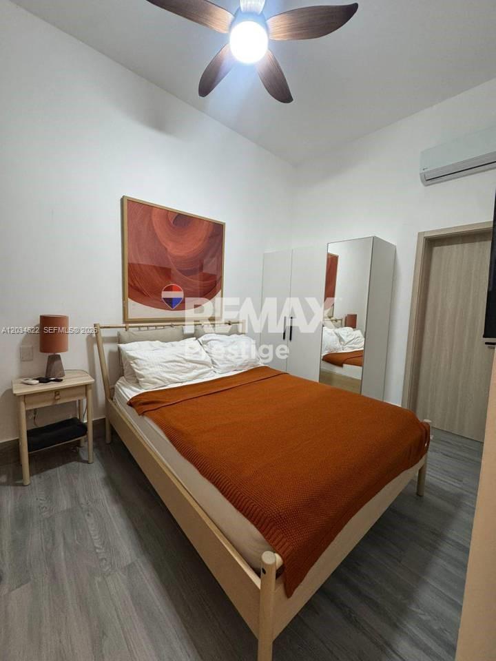 A bedroom features a bed with an orange throw, a nightstand, and a mirrored wardrobe — 1 Vista alta # 1, FL