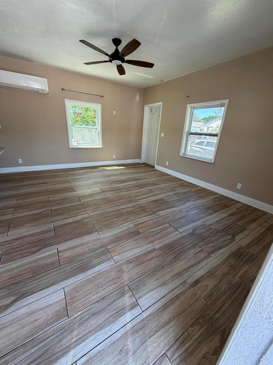 An empty room features wood-look tile flooring, a ceiling fan, and two windows — 1117 3rd Avenue N # 1, FL 33460, FL