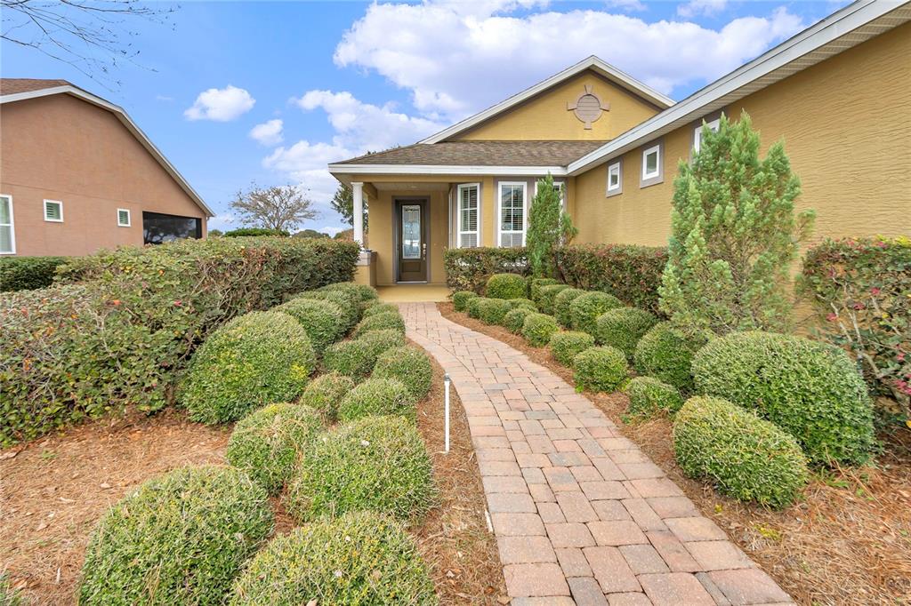 A brick walkway leads to the front entrance of a house with manicured shrubbery — 5423 NW 35TH LANE ROAD, OCALA, FL