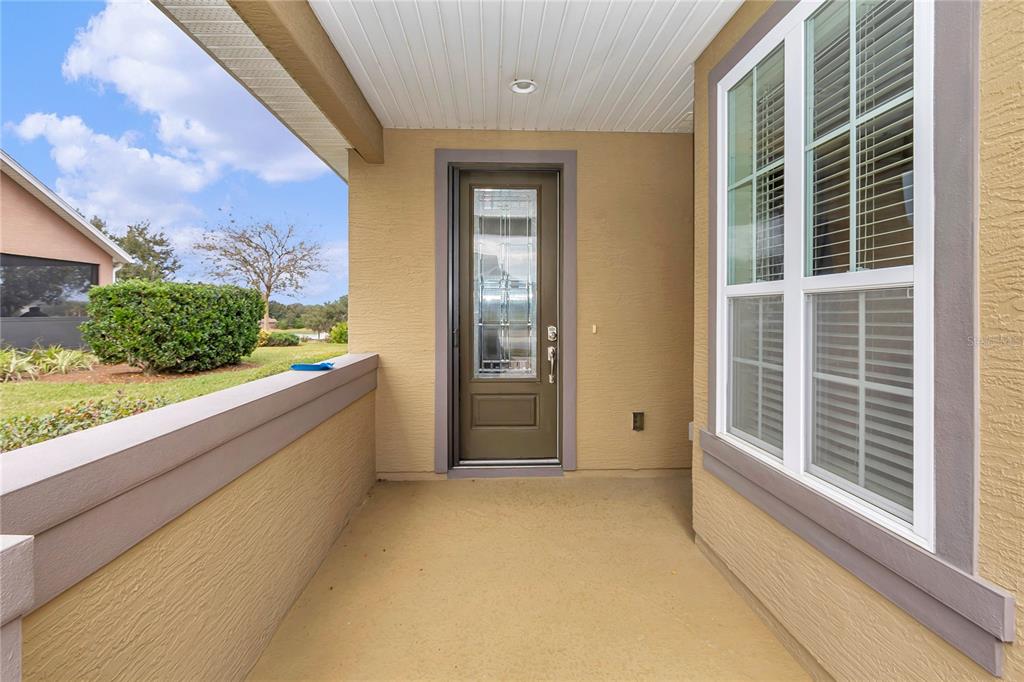 A covered front porch with a brown door, a large window, and a low wall — 5423 NW 35TH LANE ROAD, OCALA, FL