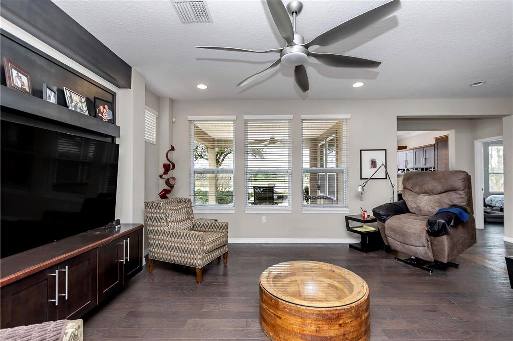 A living room features dark wood floors, a ceiling fan, a television console, and windows — 5423 NW 35TH LANE ROAD, OCALA, FL