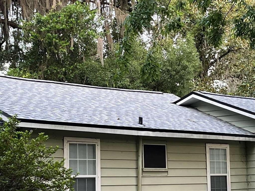 A view of a house exterior featuring a gray shingled roof and light green siding — 2432 SW 1ST ST, OCALA, FL