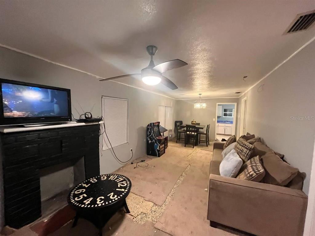 A living room features a fireplace, a ceiling fan, a sofa, and a dining area — 2432 SW 1ST ST, OCALA, FL