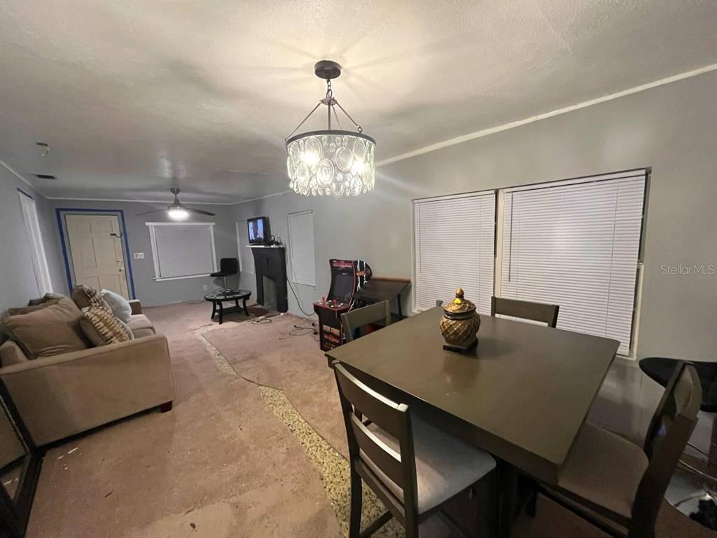 A living and dining area features carpet, a chandelier, and a small arcade cabinet — 2432 SW 1ST ST, OCALA, FL