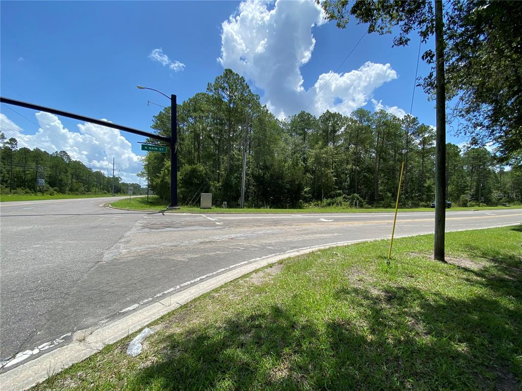 An intersection with a street sign for N Main St and a wooded lot nearby — Corner of N Main St and NE 53RD AVENUE, GAINESVILLE, FL