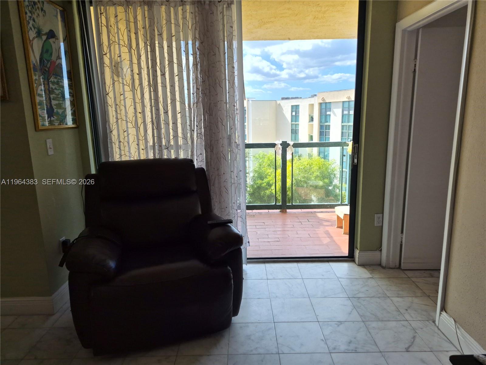 A dark leather armchair sits on a tiled floor next to a balcony sliding door — 11800 SW 18th St # 4, Miami FL 33175, MIAMI, FL