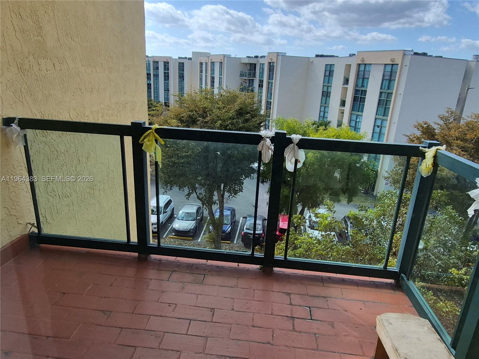 A balcony with a glass railing overlooks a parking lot and a multi-story building — 11800 SW 18th St # 4, Miami FL 33175, MIAMI, FL