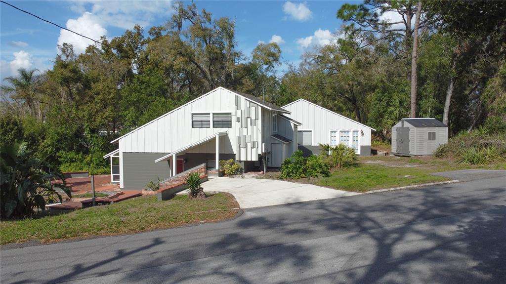 A two-story house with white vertical siding and a concrete driveway sits on a hill — 800 LAKE MARION DRIVE, ALTAMONTE SPRINGS, FL