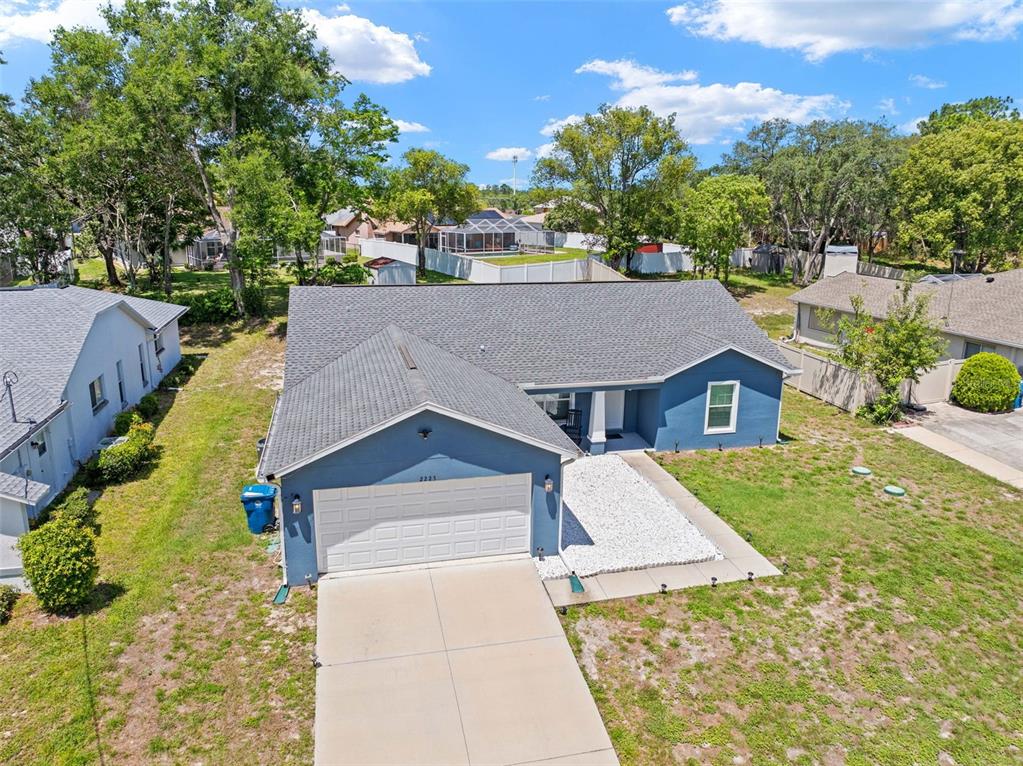 An aerial view shows a blue single-story house with a white garage door and driveway — 2225 RING ROAD, SPRING HILL, FL