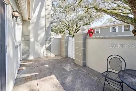 A paved patio features a small metal table and chairs next to a white wall — 11713 RAINTREE DRIVE, TAMPA, FL