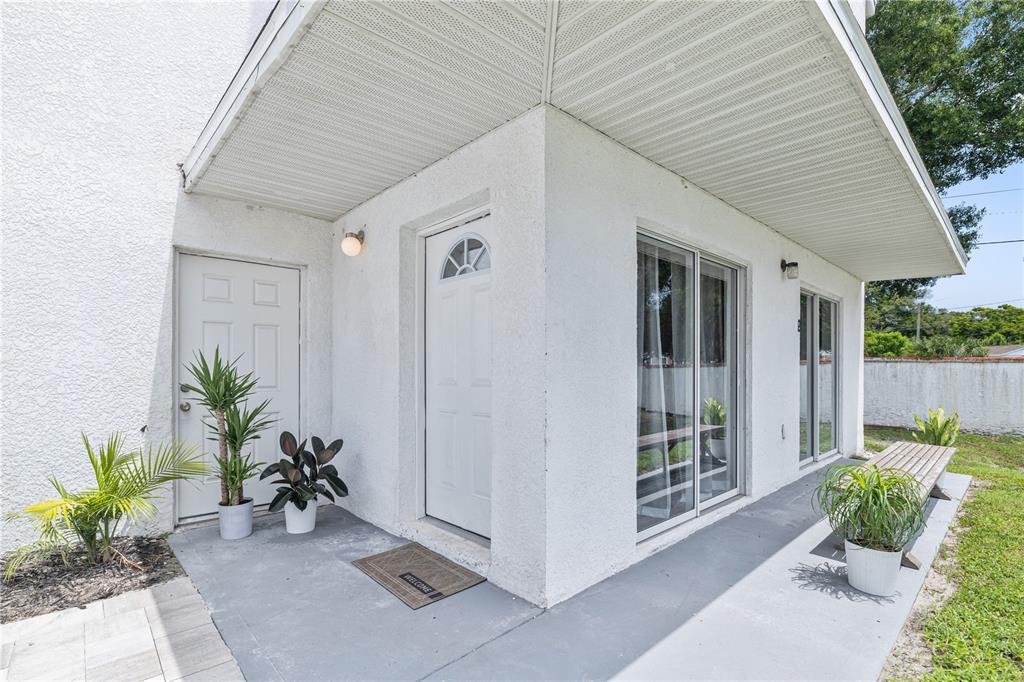 A white stucco exterior features a covered patio, a front door, and sliding glass doors — 9415 CITRUS GLEN PLACE, TAMPA, FL