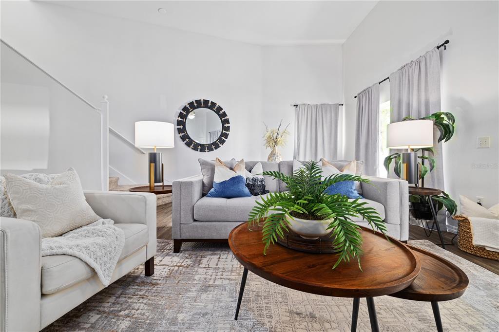 A living room features a gray sofa, white armchair, wooden coffee tables, and a round mirror — 9415 CITRUS GLEN PLACE, TAMPA, FL