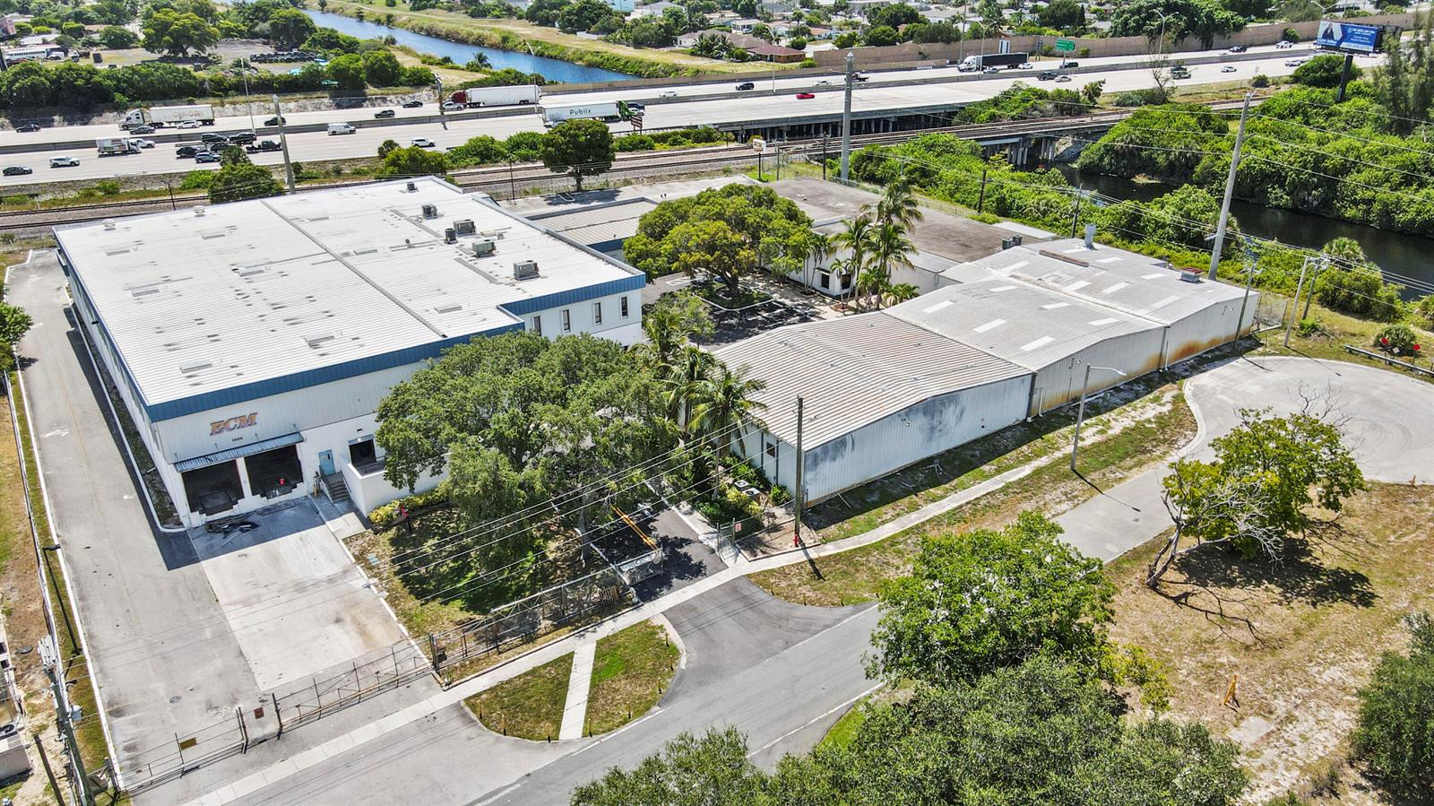 An aerial view shows two industrial warehouse buildings with metal roofs near a highway — 1500 High Ridge Road, Boynton Beach FL 33426, BOYNTON BEACH, FL